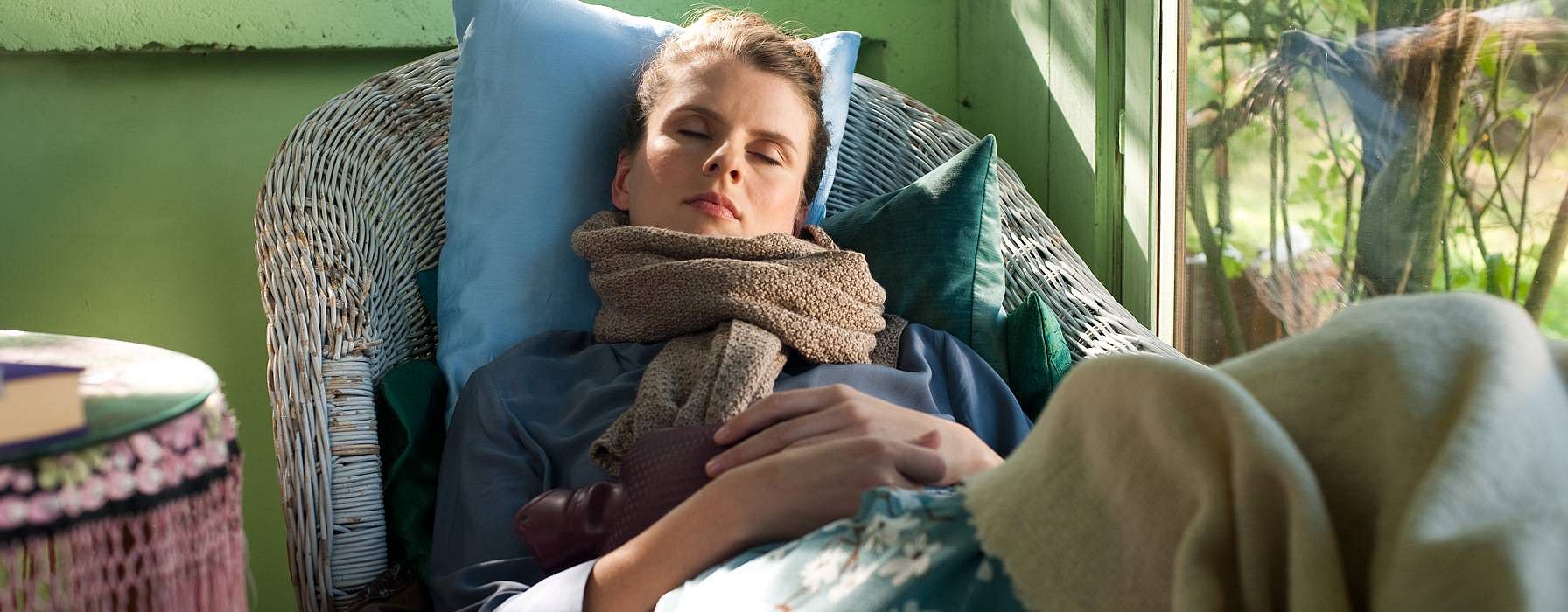 Sick woman with a warm bottle taking a nap