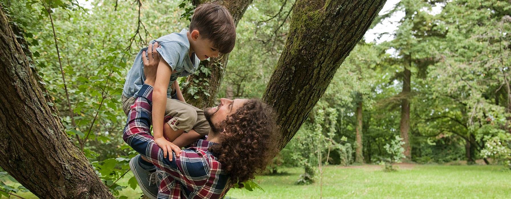 father lifting boy in forest