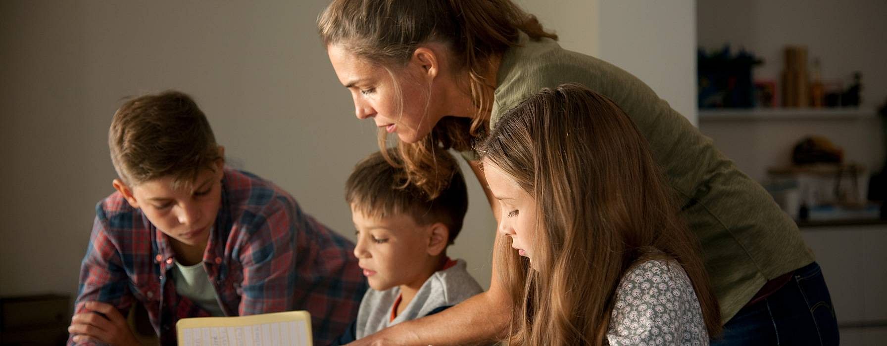 Mother doing homework with her 3 children