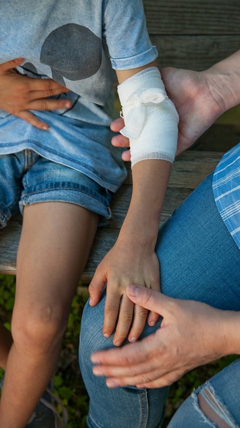 Mother caring for hurt arm on boy