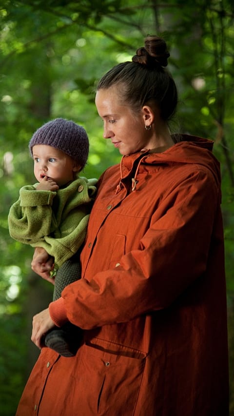 Mother carrying baby in woods