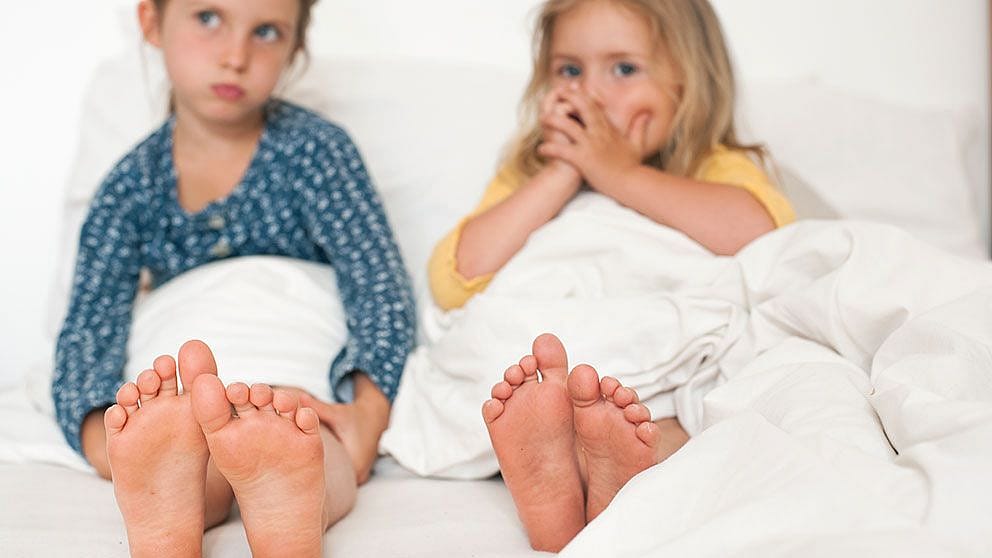 2 children in bed showing feet