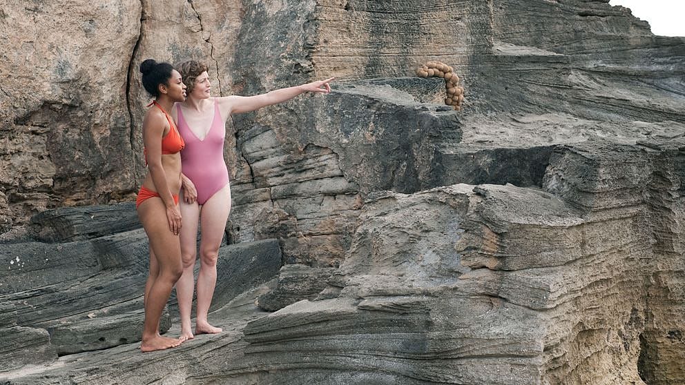 two girls on rocks near water